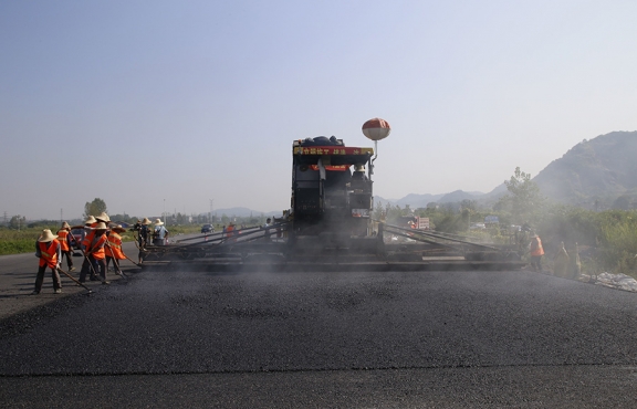 2019年8月，宜春經(jīng)開區(qū)S311路面攤鋪現(xiàn)場，工友們輔助路面兩側(cè)的分料、補窩等作業(yè)